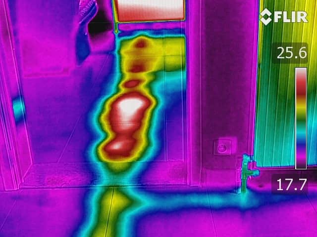 Op de thermische opname is een duidelijk warmteverlies te zien in de vloer, met een warme streep van de radiator naar een leiding onder de tegelvloer. Dit benadrukt hoe onzichtbare waterlekkage en een leidingbreuk met infraroodlekdetectie snel en nauwkeurig worden opgespoord. Met deze methode kunnen vocht- en plafondschade vroegtijdig worden ontdekt, waardoor gerichte reparatie mogelijk is zonder onnodig hak- en breekwerk. Zo toont deze foto het belang van professionele lekdetectie en herstel voor een droge en veilige woning.